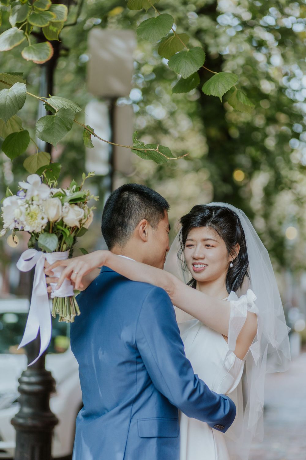 A couple shares a tender moment under blooming trees on their wedding day.