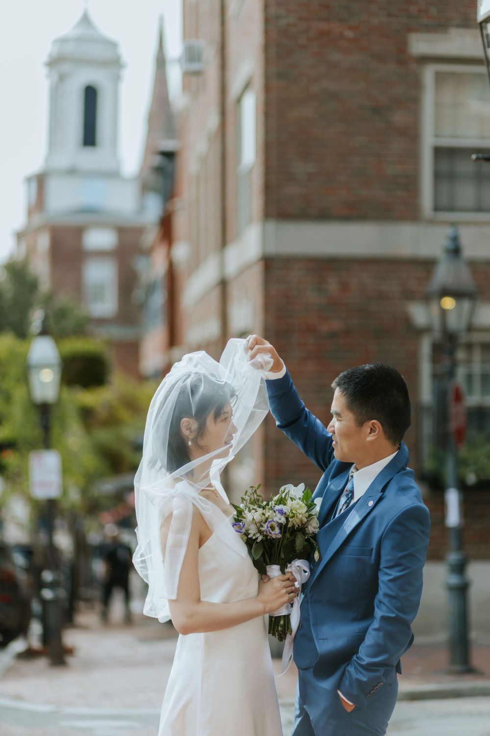 A wedding couple posing on a historic street with church spires in the background.