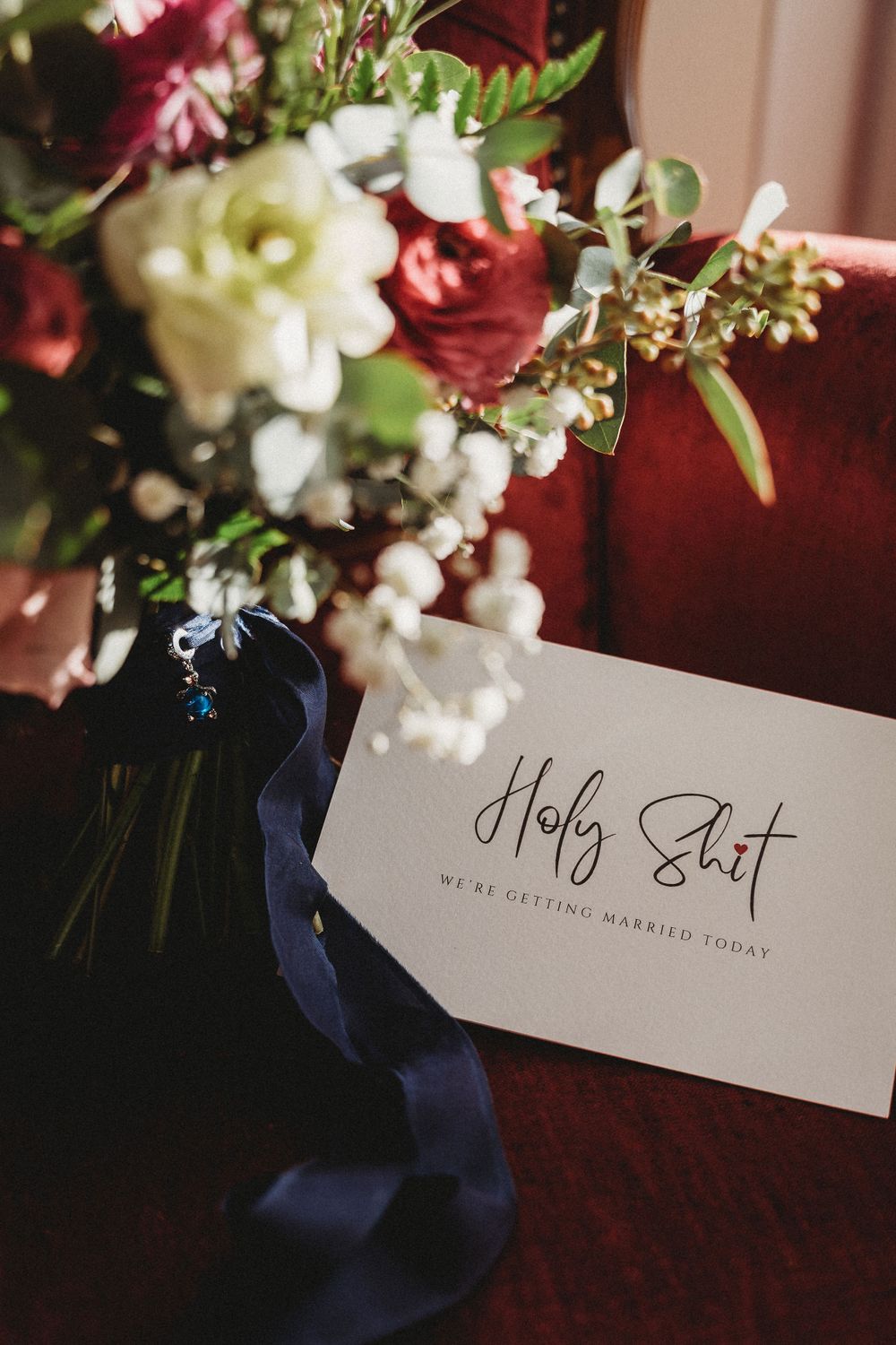 Wedding place cards with calligraphy displayed among red and white floral arrangements.