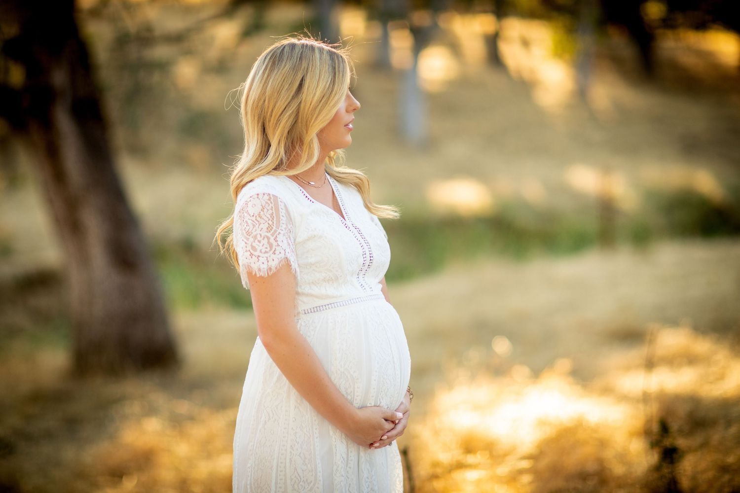 A maternity photoshoot captures glowing moments in a sun-drenched outdoor setting at sunset.