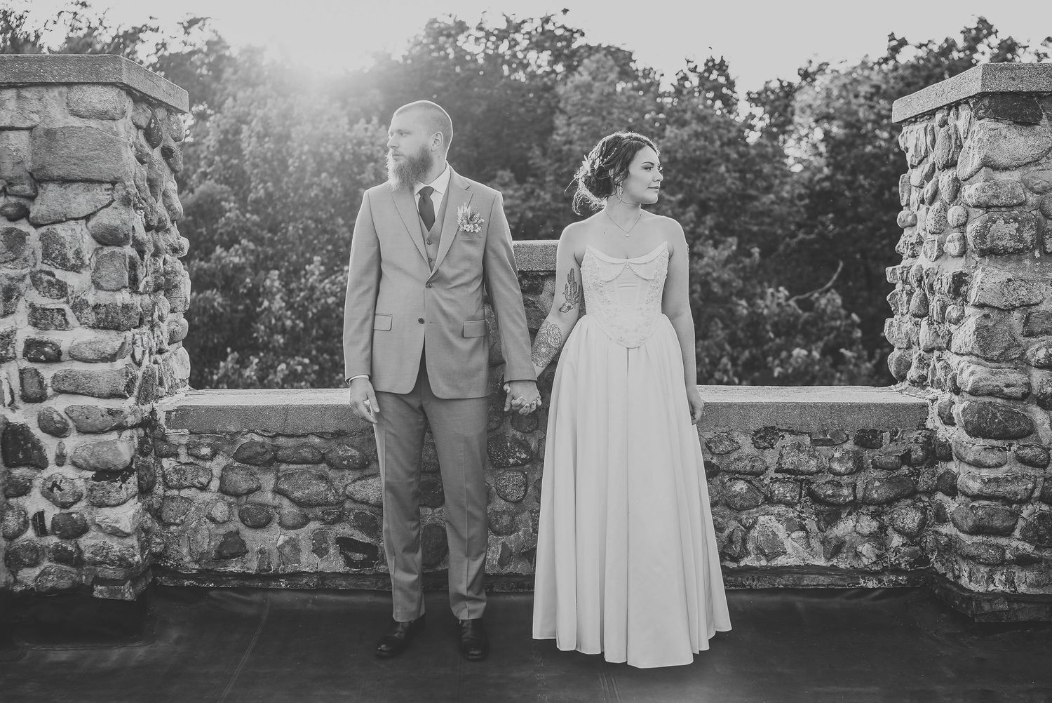 A couple sitting in a classic car with a bridal bouquet in black and white.