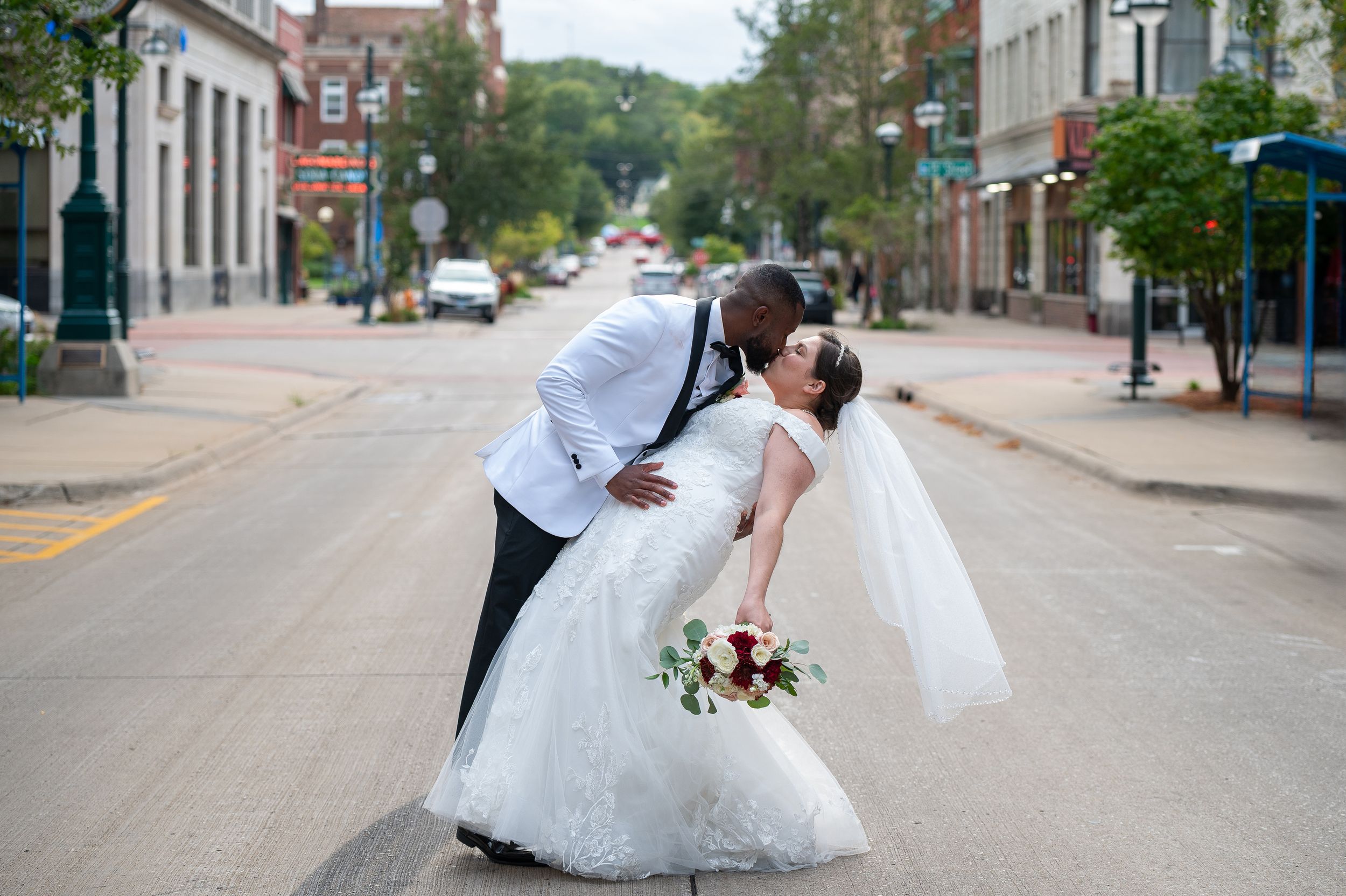Bride and groom share a romantic dip kiss in the middle of a charming downtown street on their wedding day.