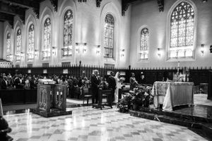 Black and white photo of church interior with gothic windows and elegant ceremony setup.