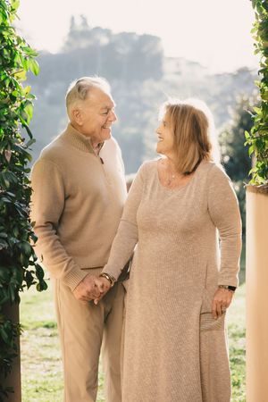 Older couple holding hands with a softly blurred city view behind them.