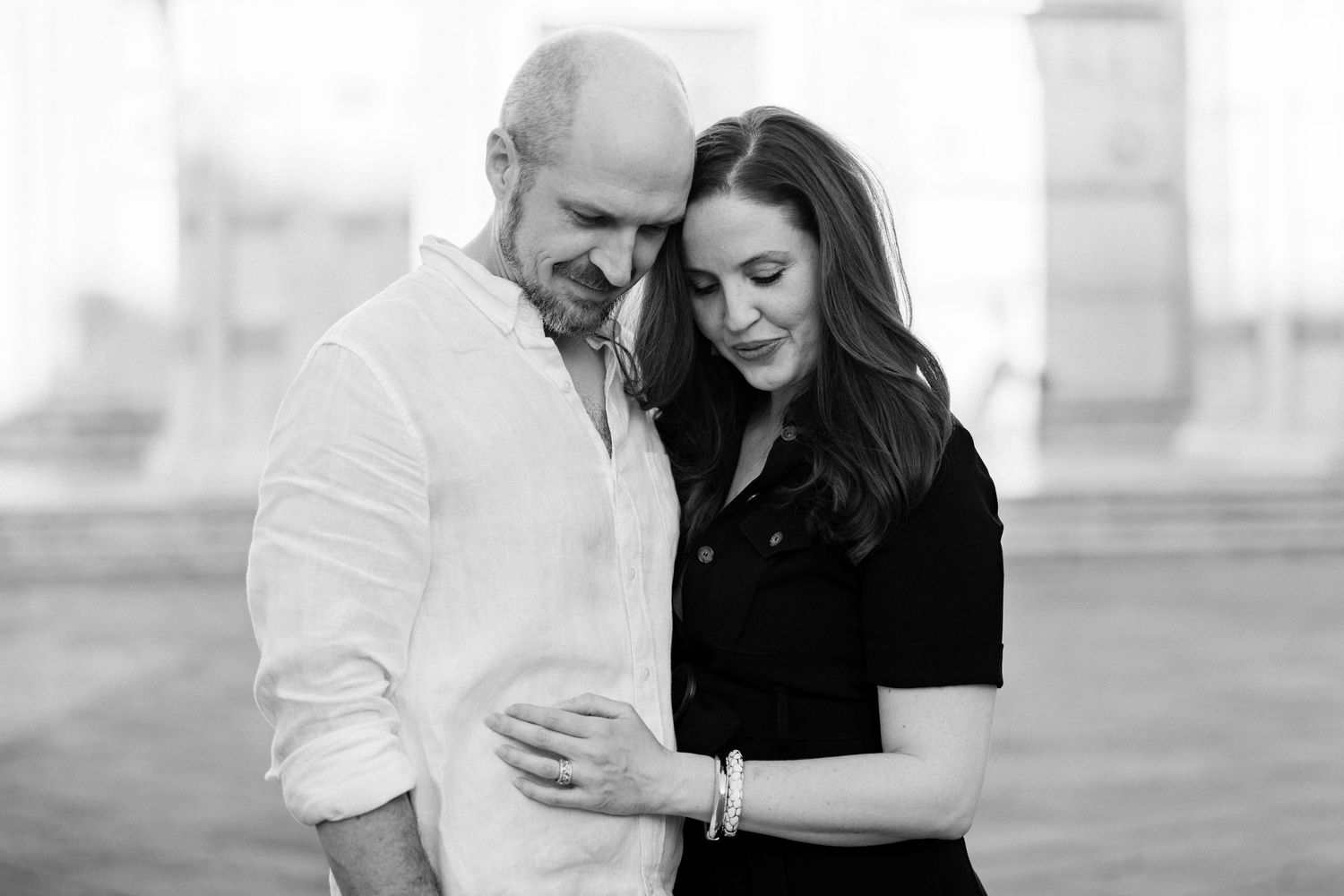 Expectant couple sharing a quiet moment in a black-and-white portrait.