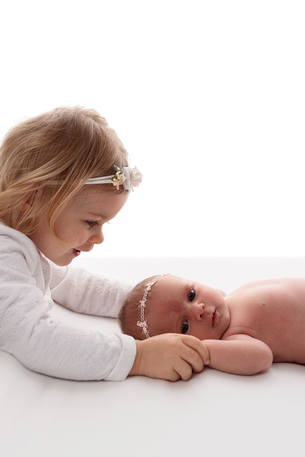 Two siblings sharing a tender moment together against a white background.