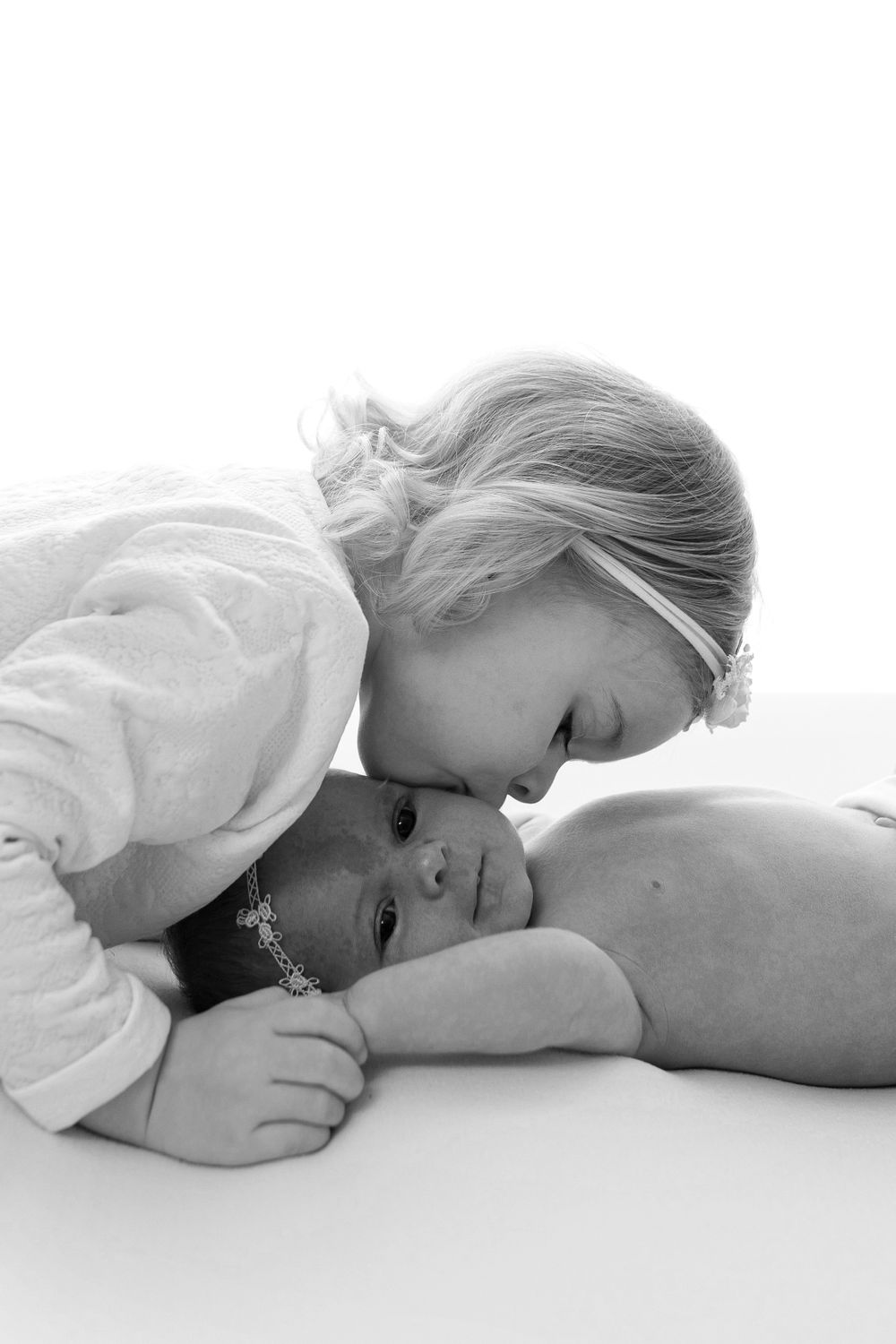 Black and white portrait of siblings bonding together on white backdrop.