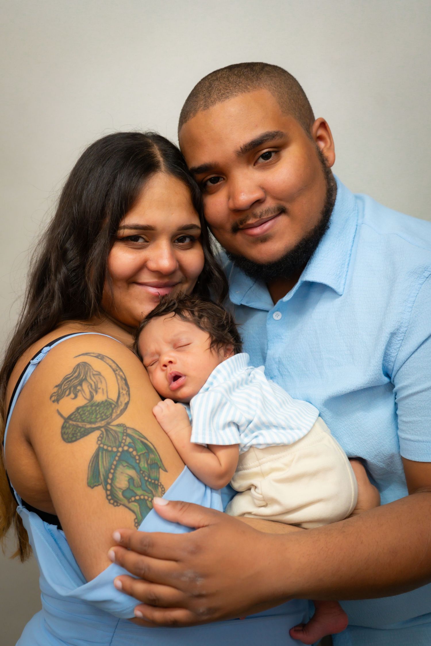 Family portrait in matching white outfits against neutral background.