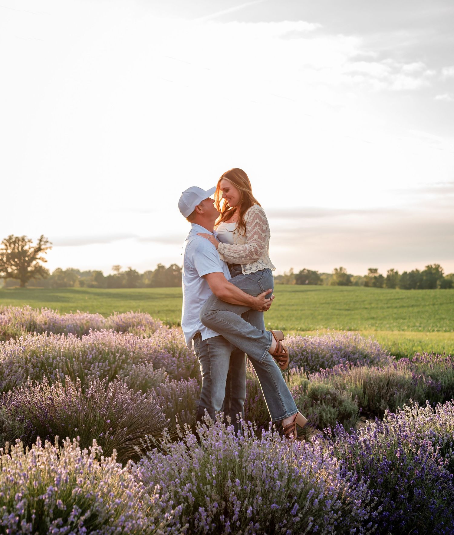 Intimate maternity photo of couple in casual attire against rustic wooden wall background.