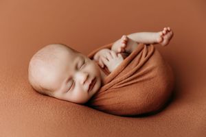 Artistic newborn photography on warm terracotta background showing peaceful sleeping poses.