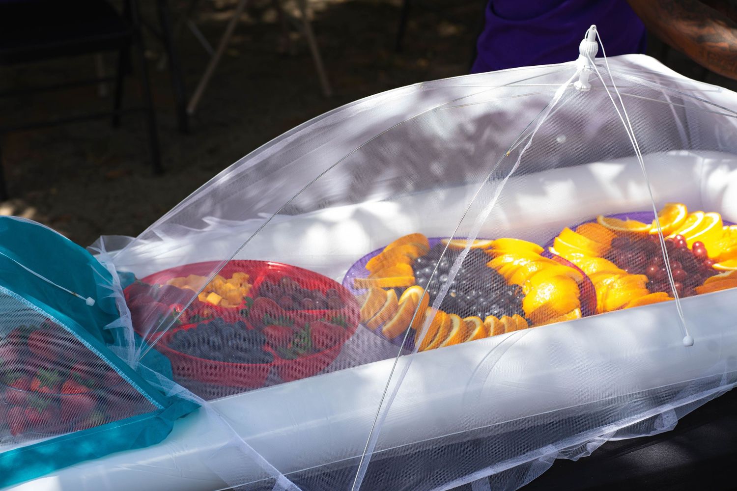 Fresh peaches displayed under clear protective covering at a market or event.