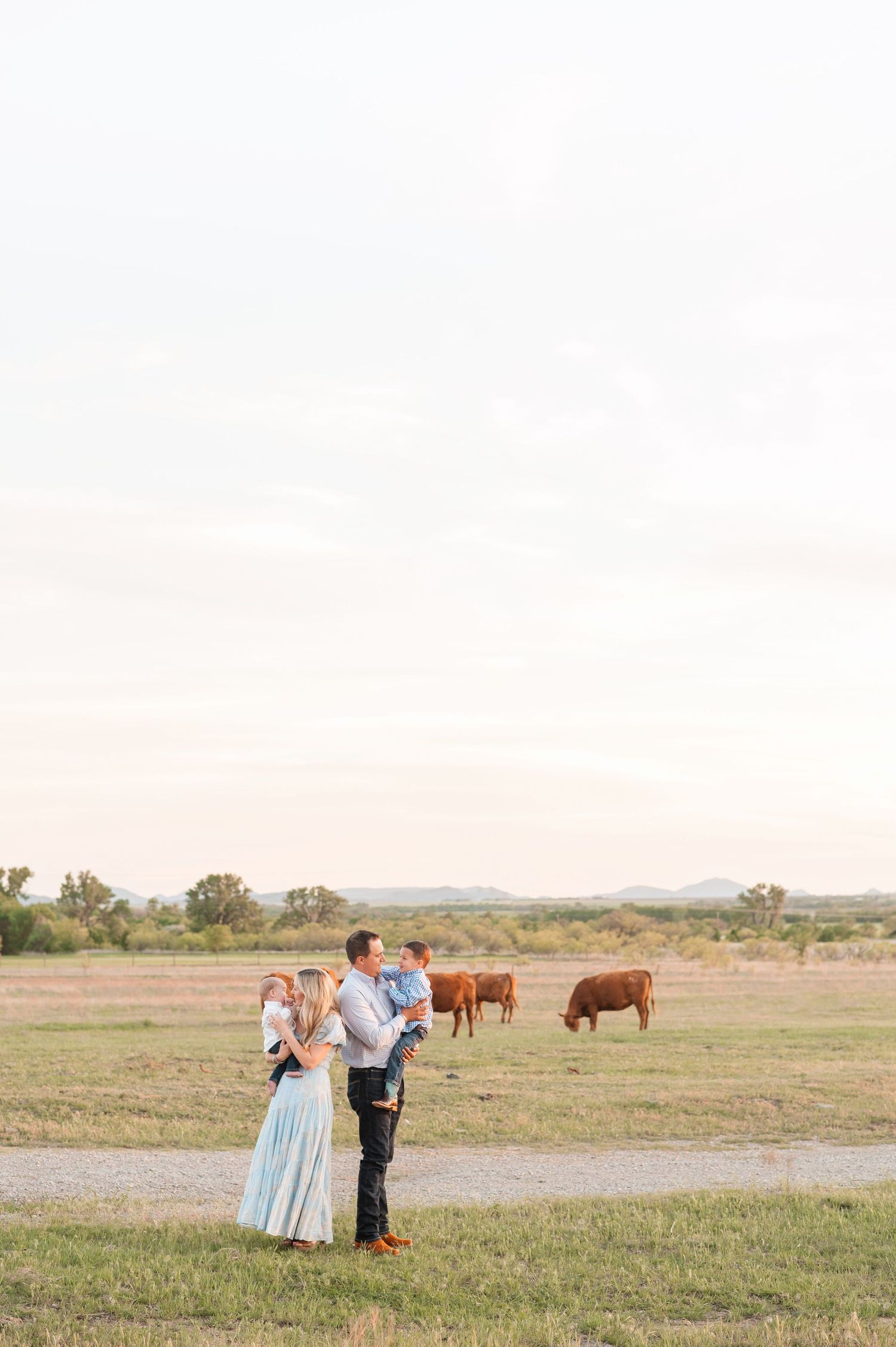 A family of four posing in coordinated outfits in a scenic outdoor location.
