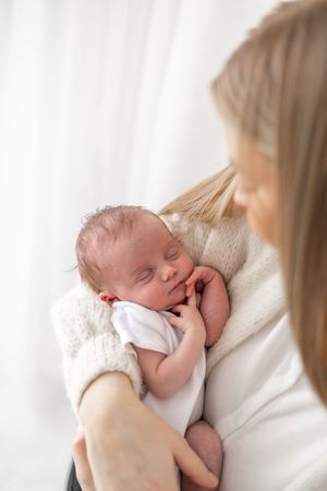 Newborn photoshoot Nottingham natural light baby portrait in new mums arms cosy studio