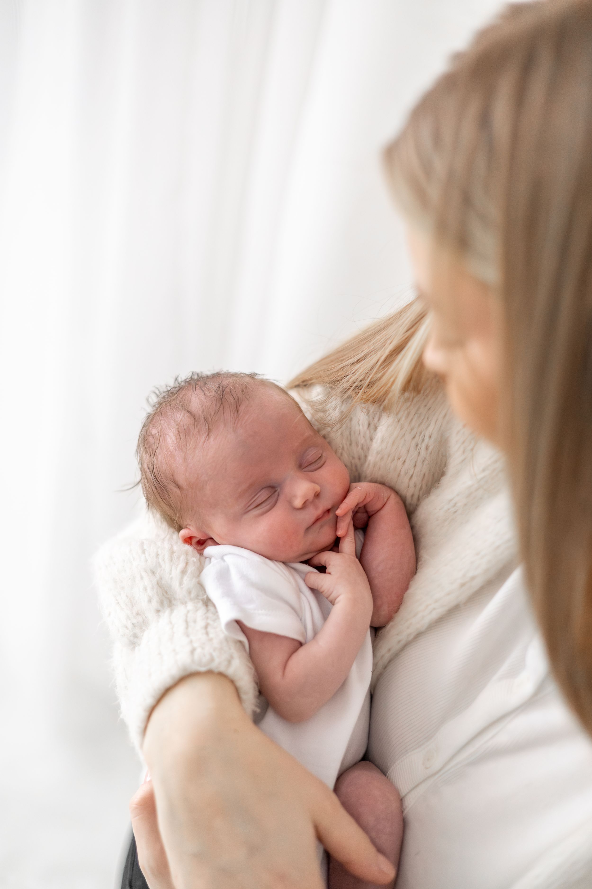 Newborn photoshoot Nottingham natural light baby portrait in new mums arms cosy studio