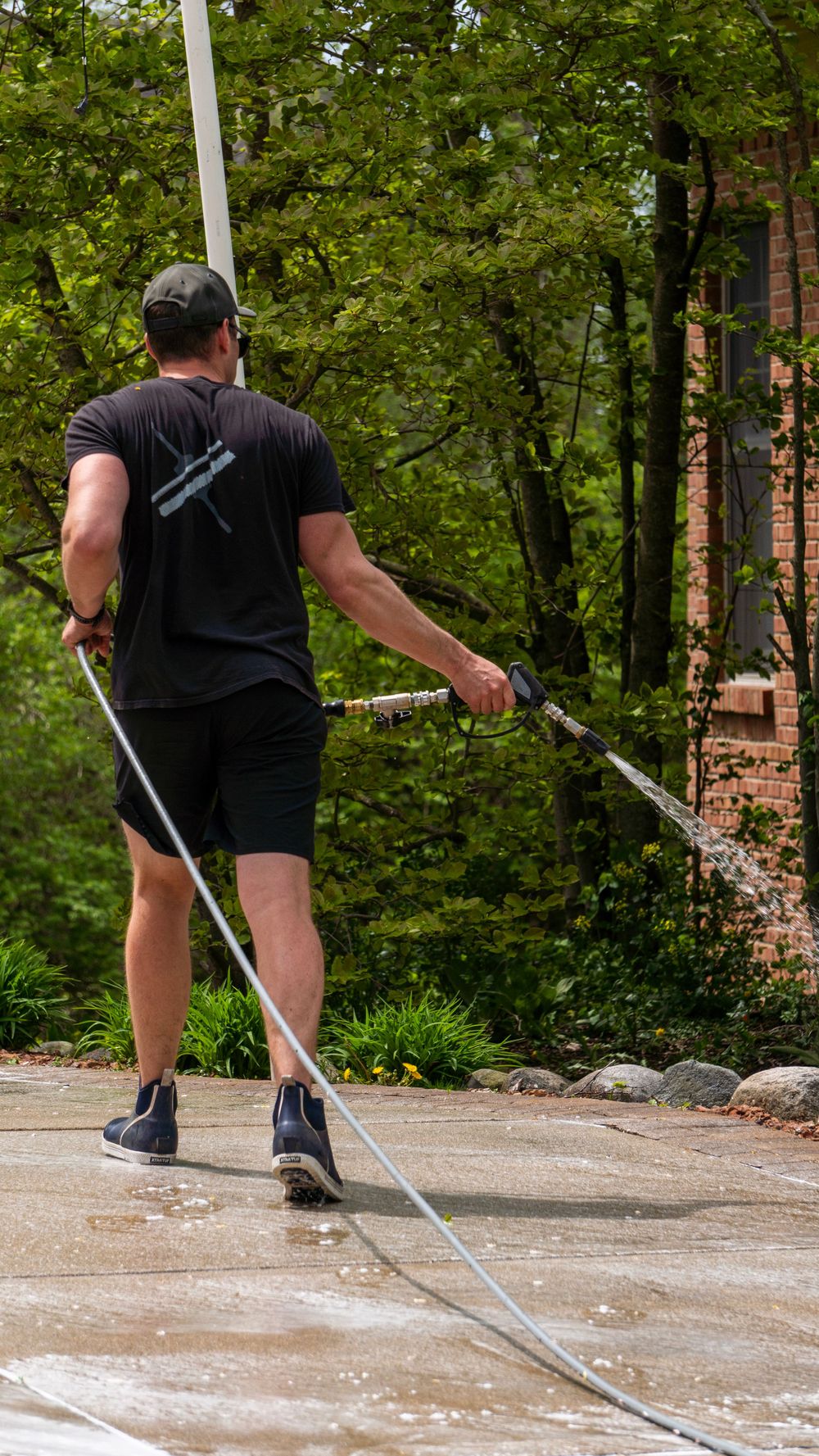 A man spraying a driveway with a hose