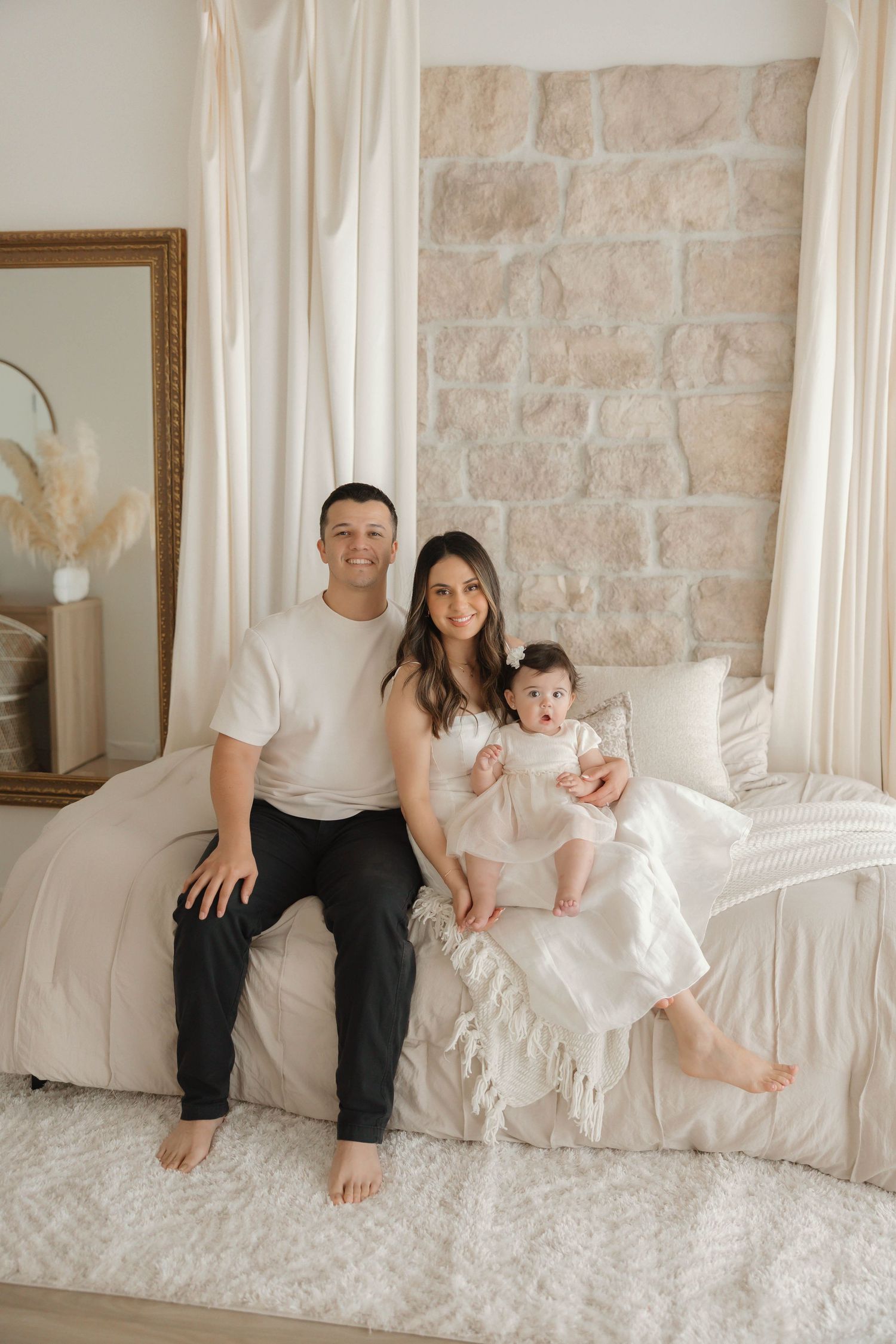 Relaxed maternity photo of couple in casual wear sitting on floor by window at studio in Huntington Beach