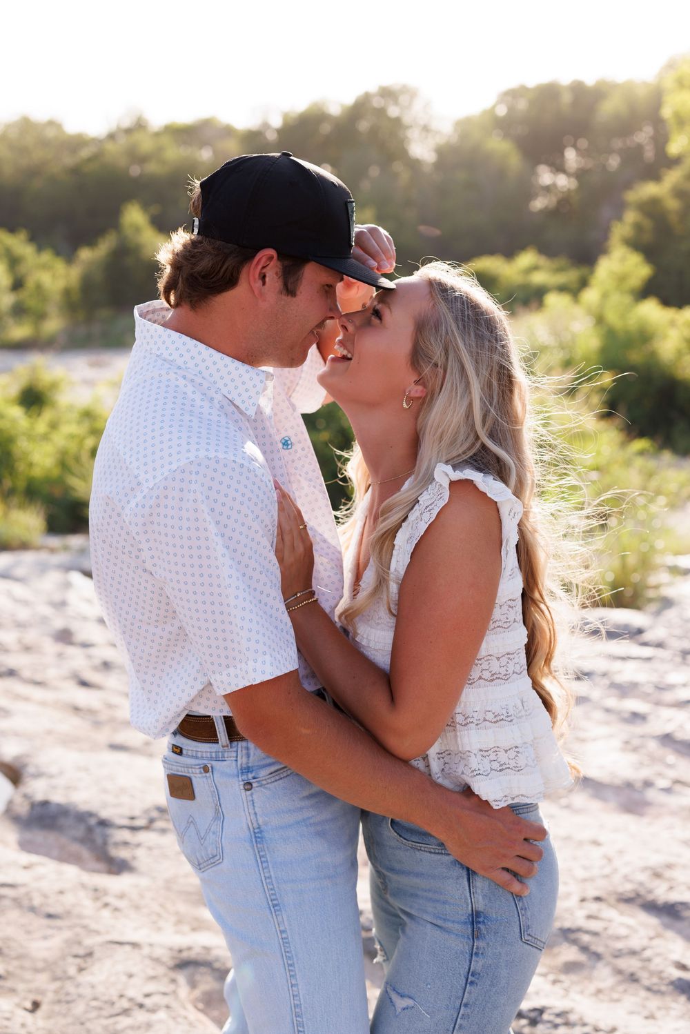 Couple in matching light denim sharing intimate moment on sandy beach at sunset.