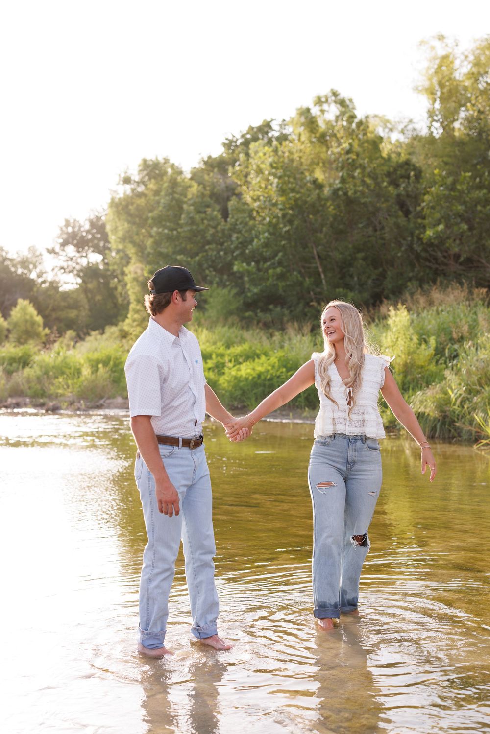 Couple splashing and playing in shallow water at sunset.