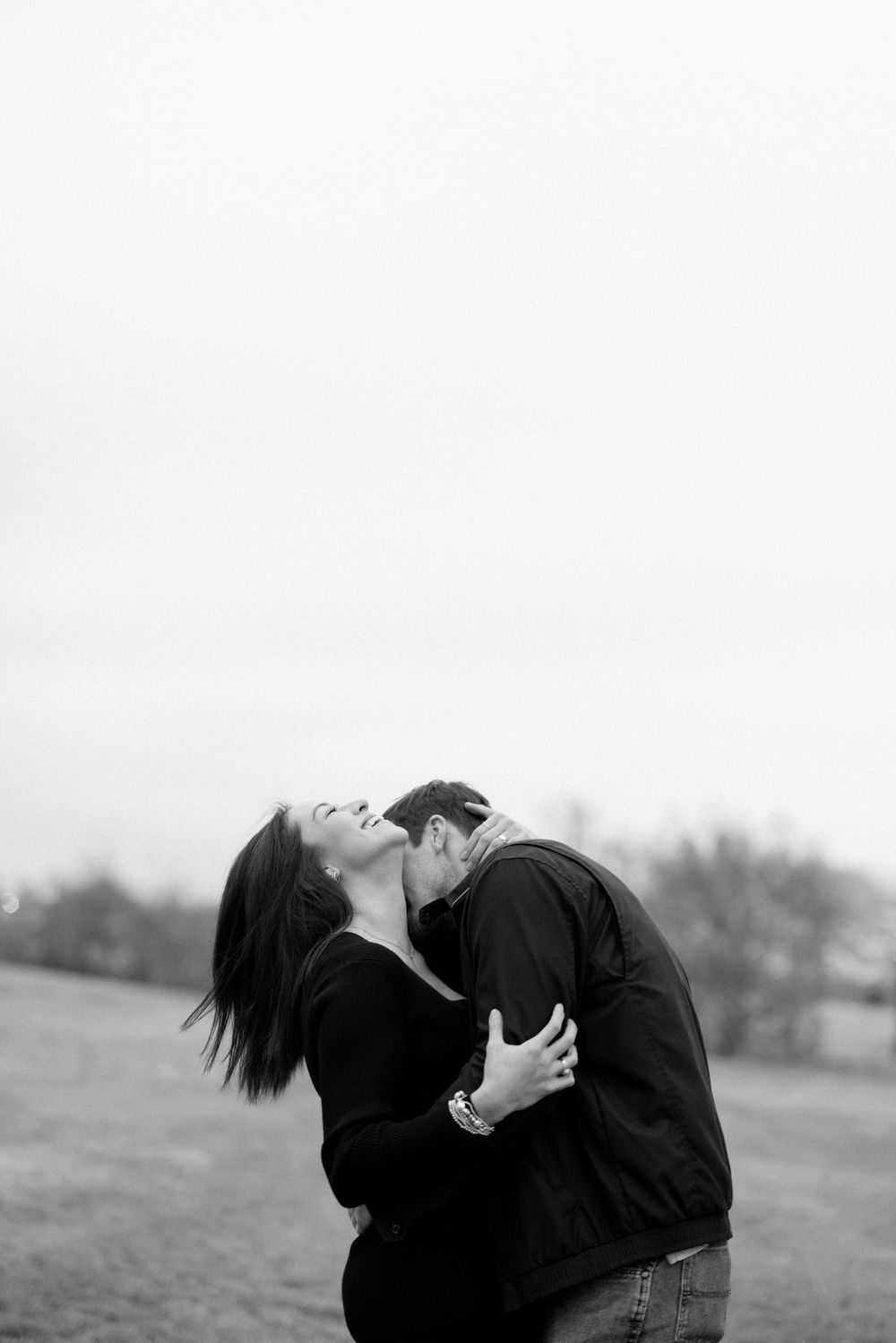 Romantic black and white photo of couple embracing in a field.