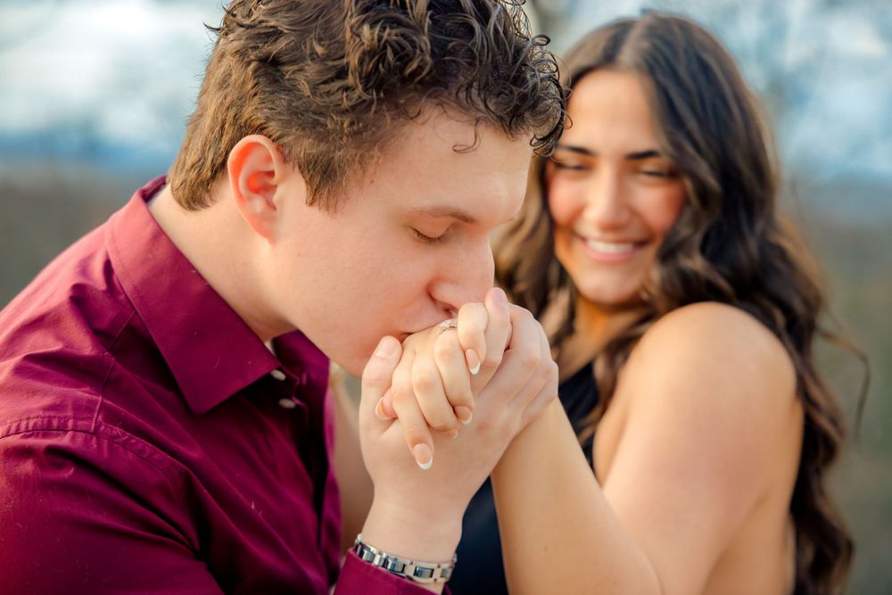Couple shares intimate moments on an outdoor deck with mountain views in the background.