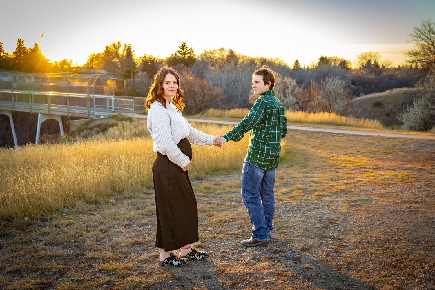 a couple stand in front of a bridge.