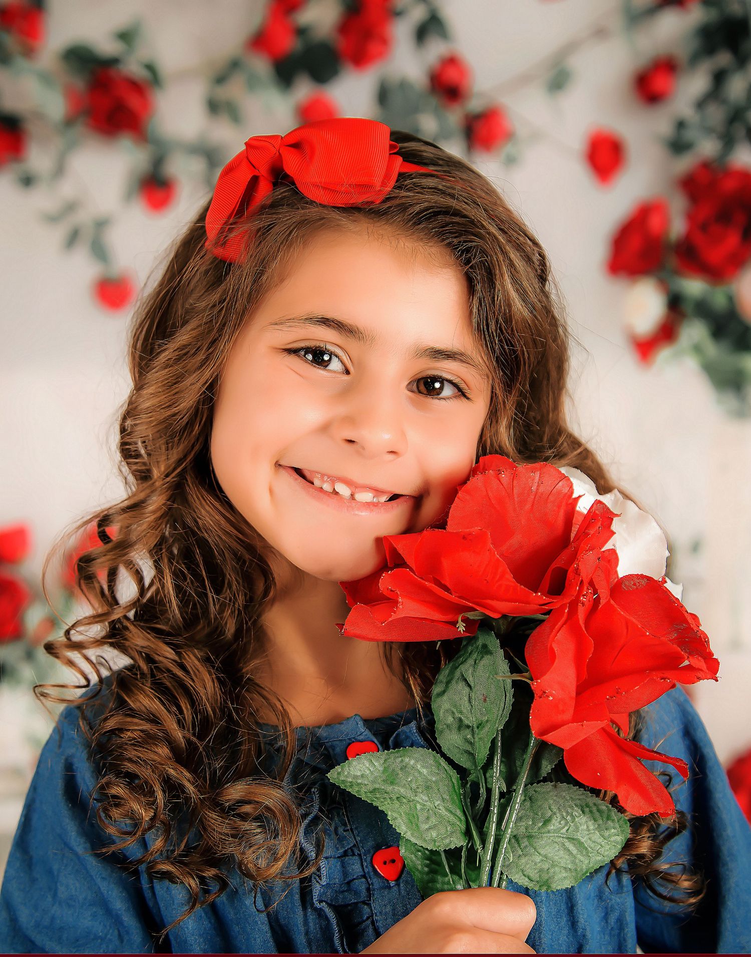 A young child in blue poses with vibrant red roses against a light backdrop in a series of artistic portraits.