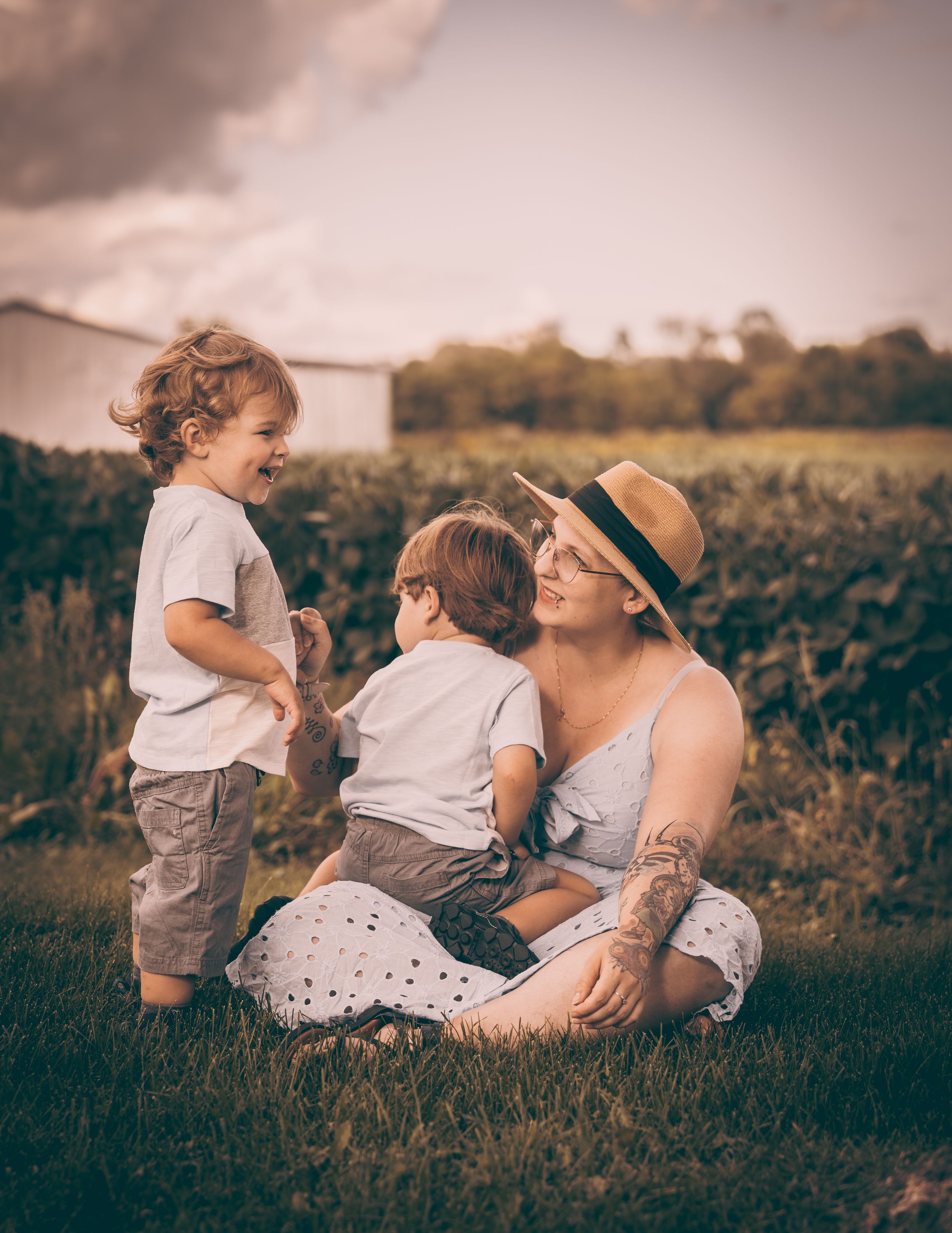 Candid family moment captured in a summer field at sunset.