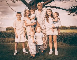 Large family group portrait outdoors in coordinated light-colored outfits.