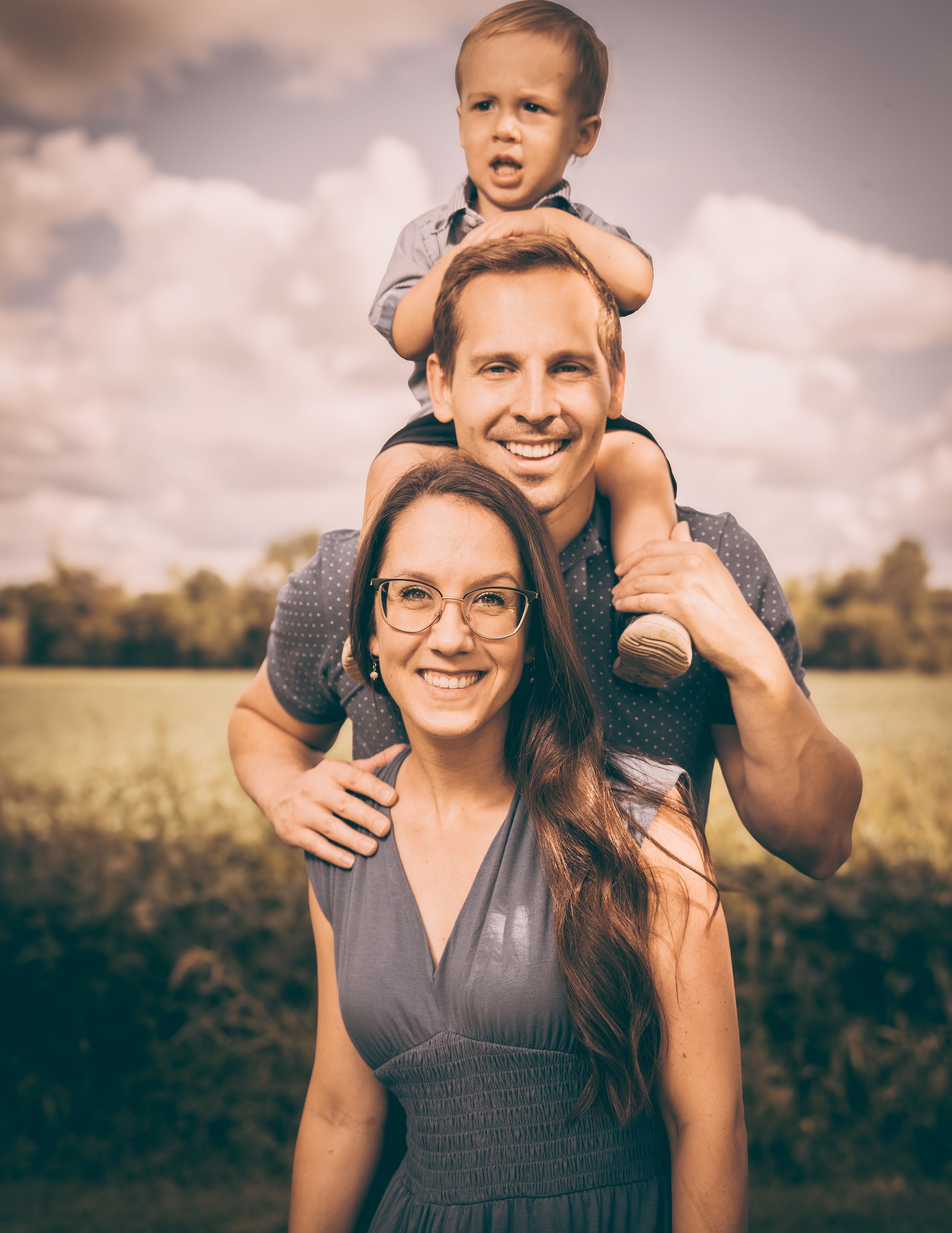 Joyful family portrait in a sunny meadow during golden hour.