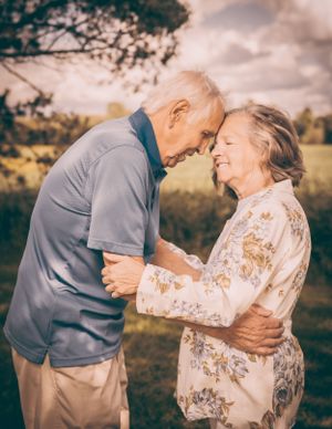 Elderly couple sharing an intimate moment outdoors in a natural setting at sunset.