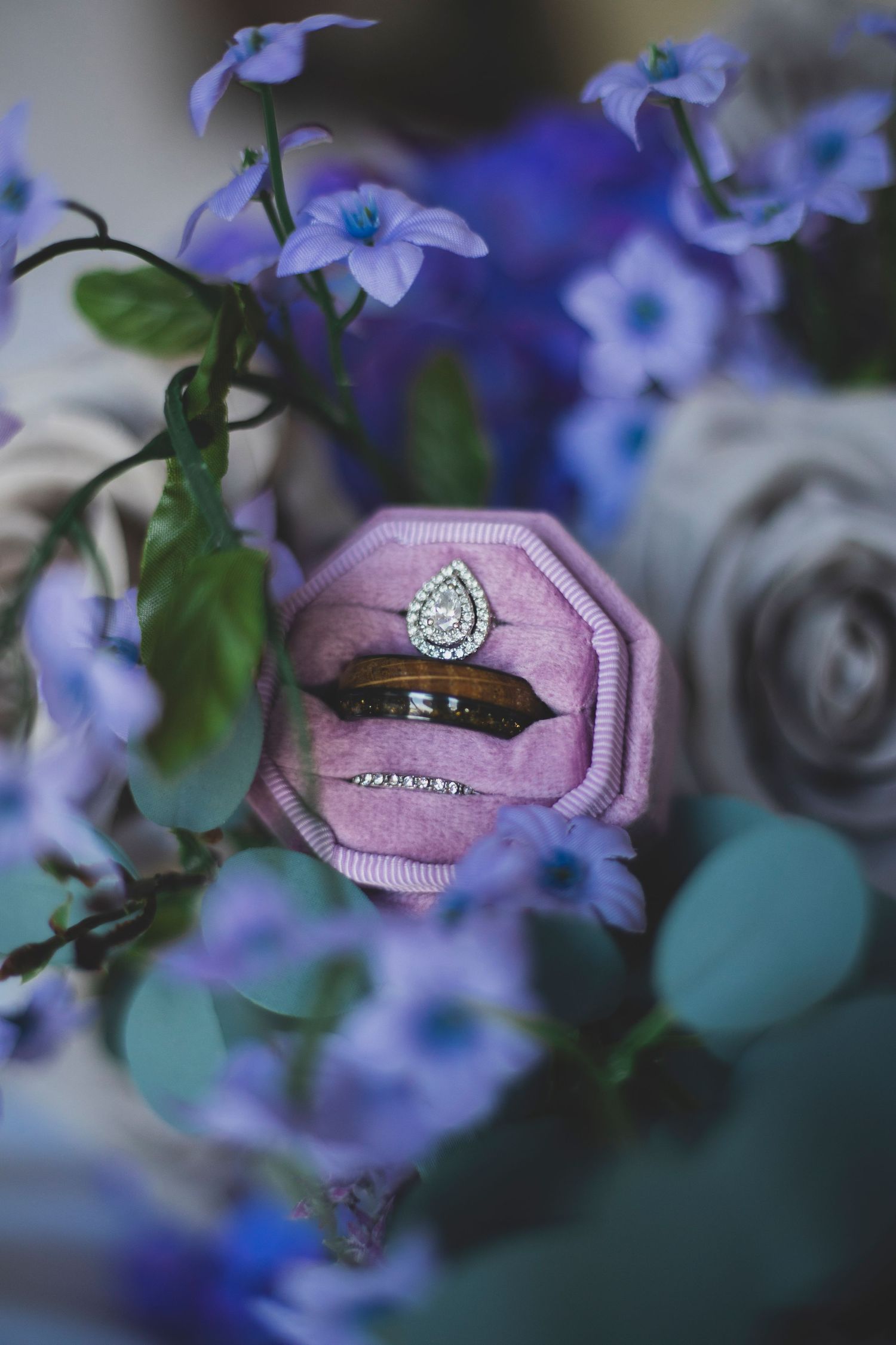Wedding rings nestled among delicate blue flowers and pink fabric.