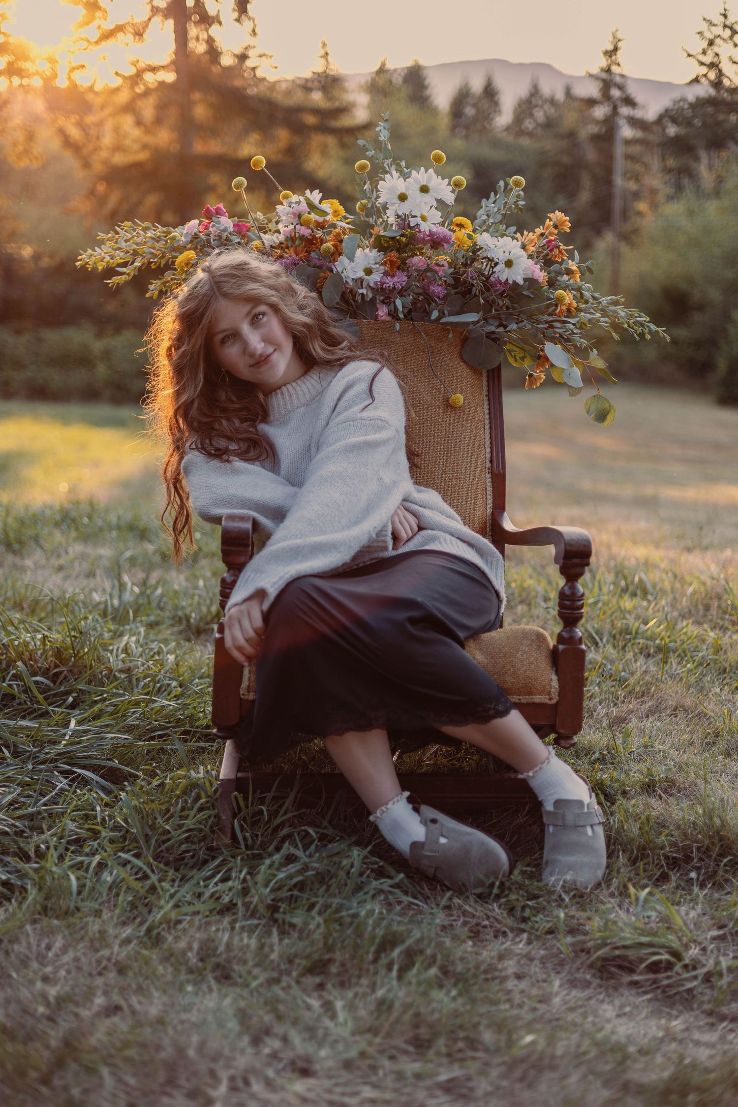 Dreamy sunset portrait in a vintage chair with wildflower arrangement.