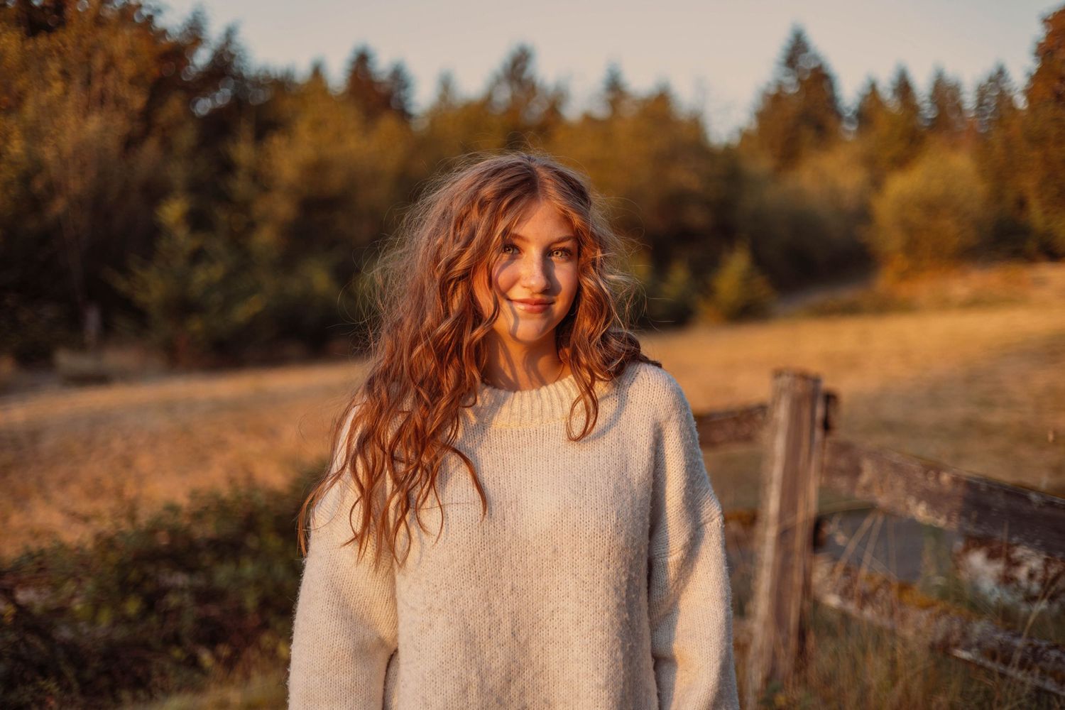 Candid sunset portrait in cream sweater with mountain landscape backdrop.