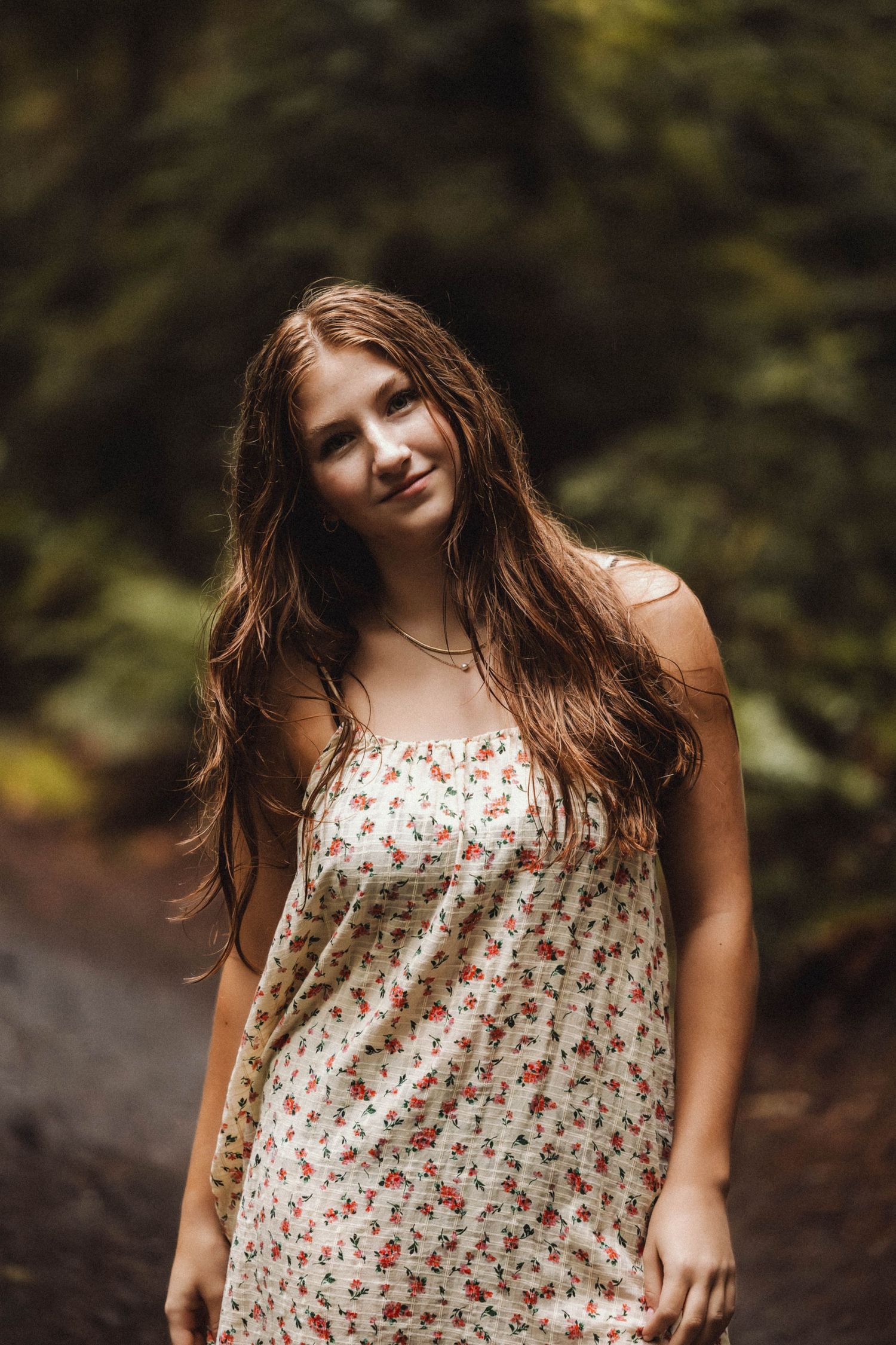 Natural outdoor portrait on a wooded path wearing a white floral sundress.