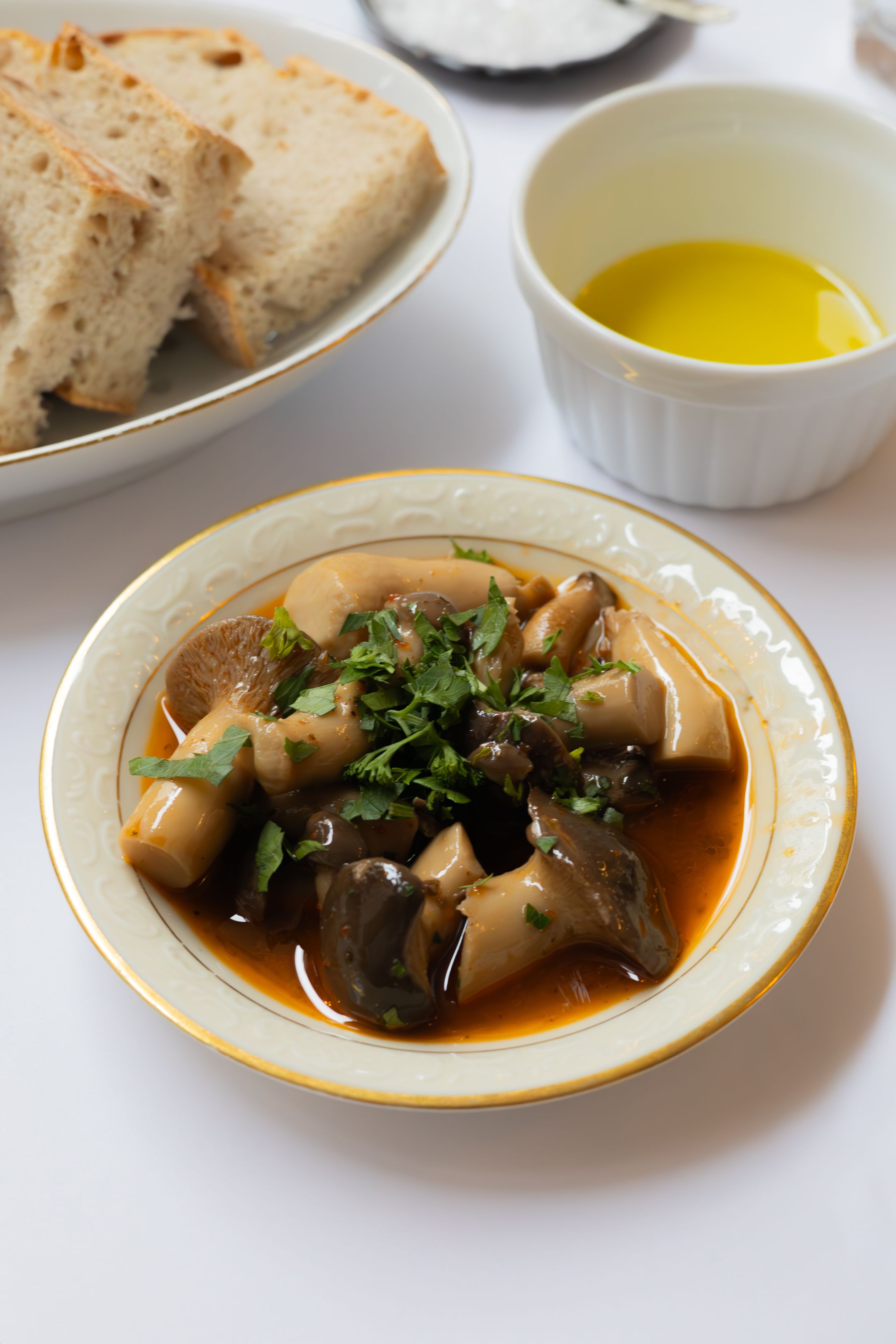 Mushroom stew garnished with fresh herbs served with bread and olive oil.