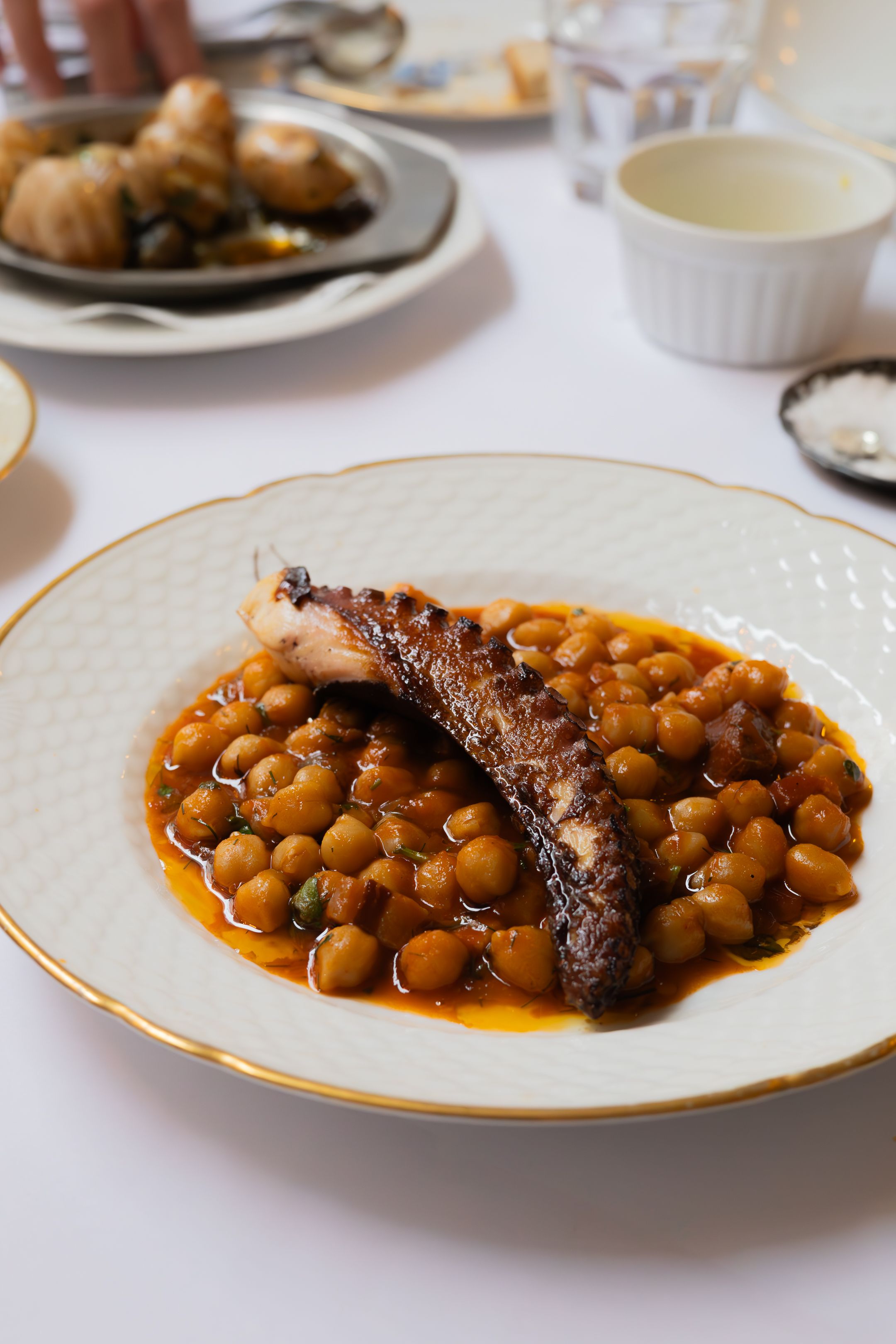 A grilled meat dish served with stewed chickpeas in savory sauce.
