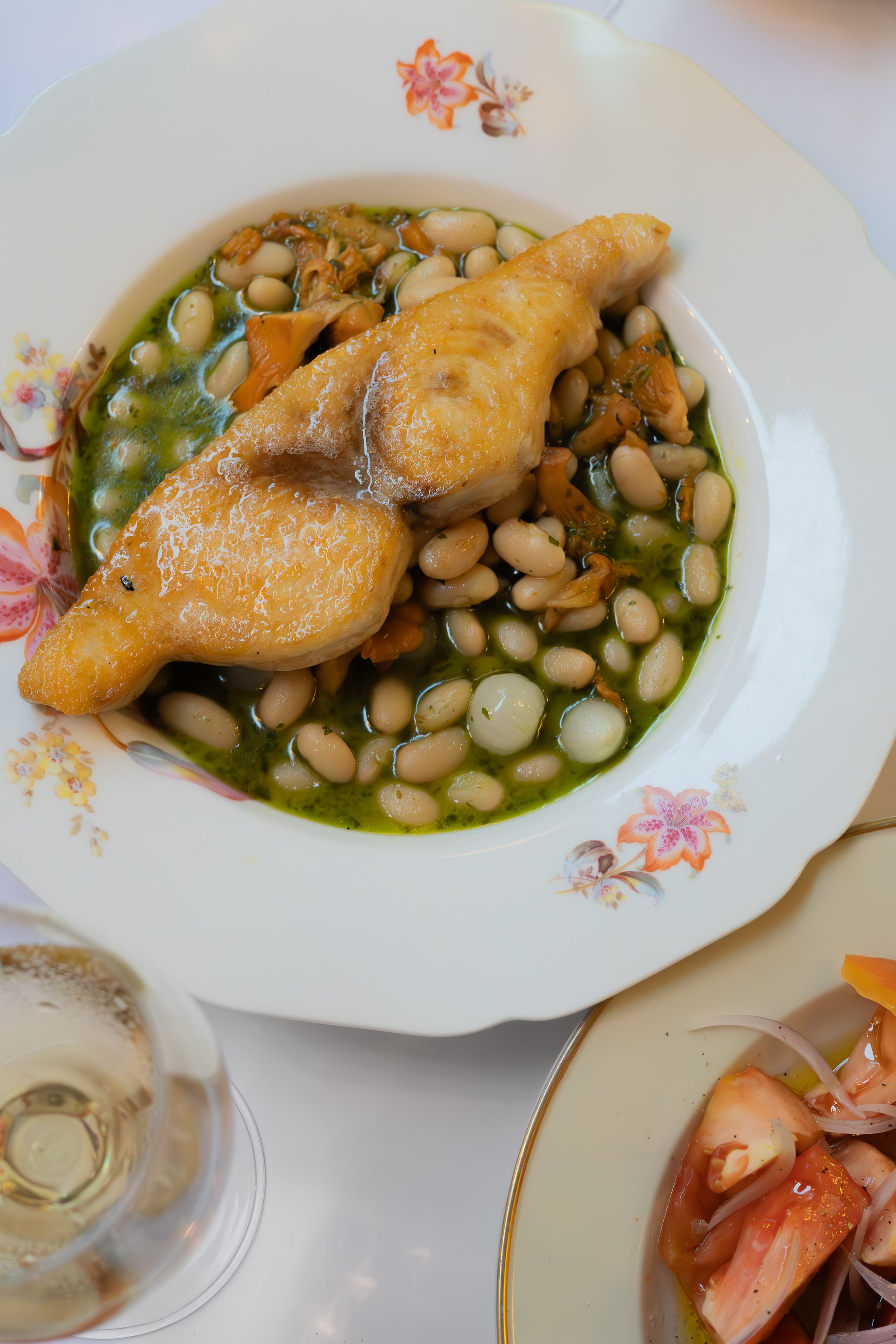 Golden fried chicken served over white beans in herb-infused broth.