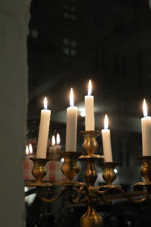 Elegant brass candelabra with lit white candles reflecting in dark mirror.