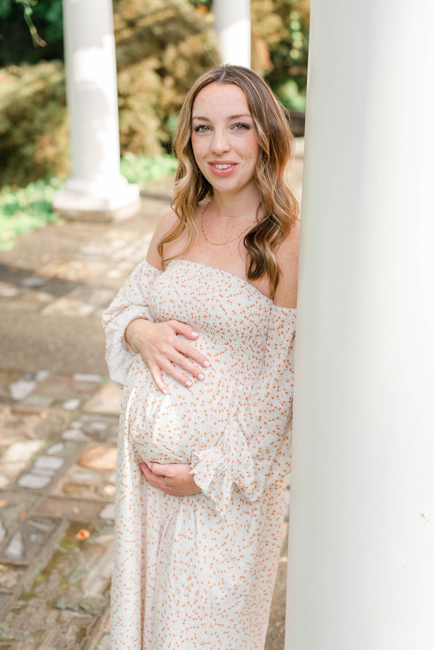 An elegant maternity photo featuring a flowing off-shoulder floral dress.