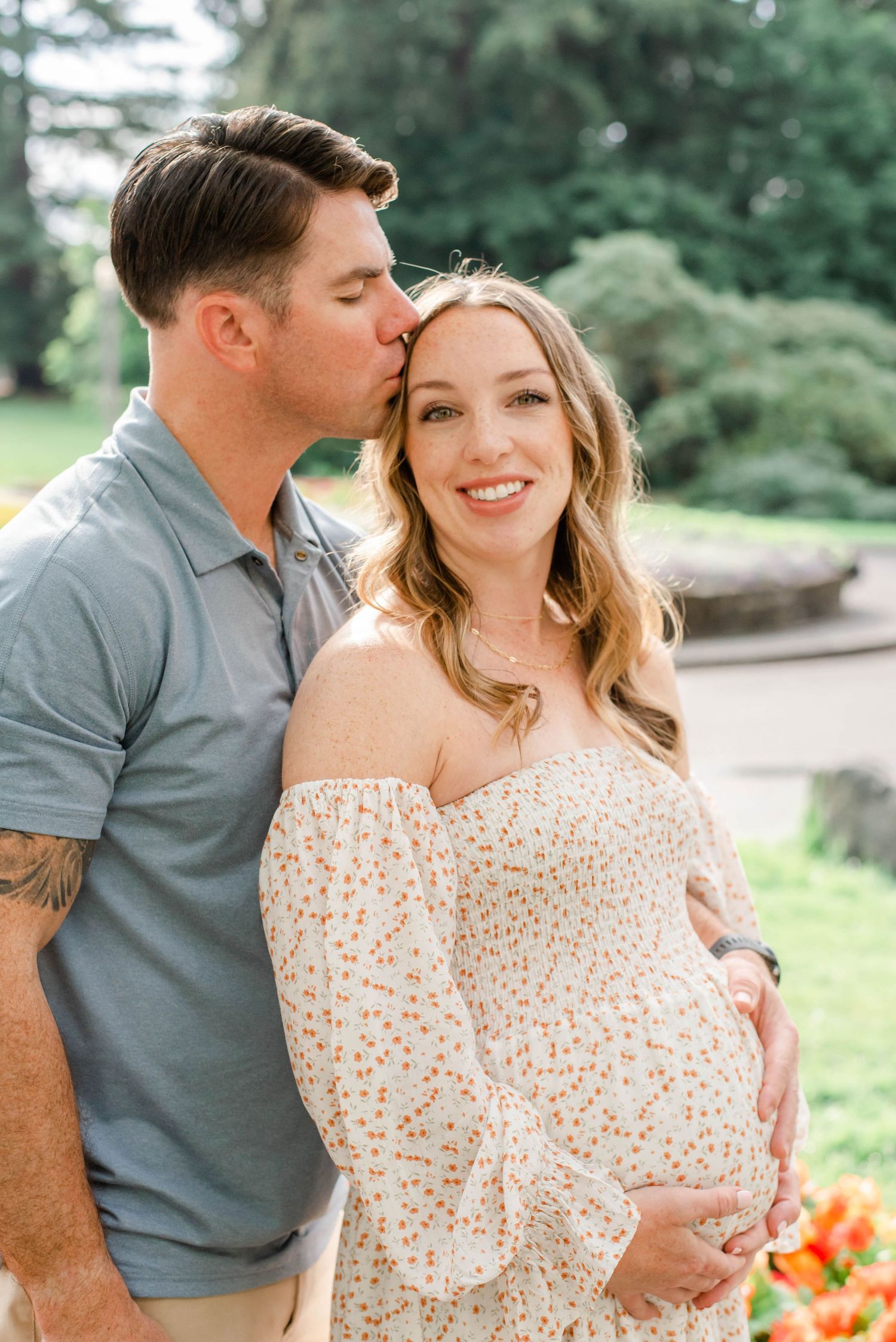 Sweet maternity moment captured in garden setting with blooming flowers.