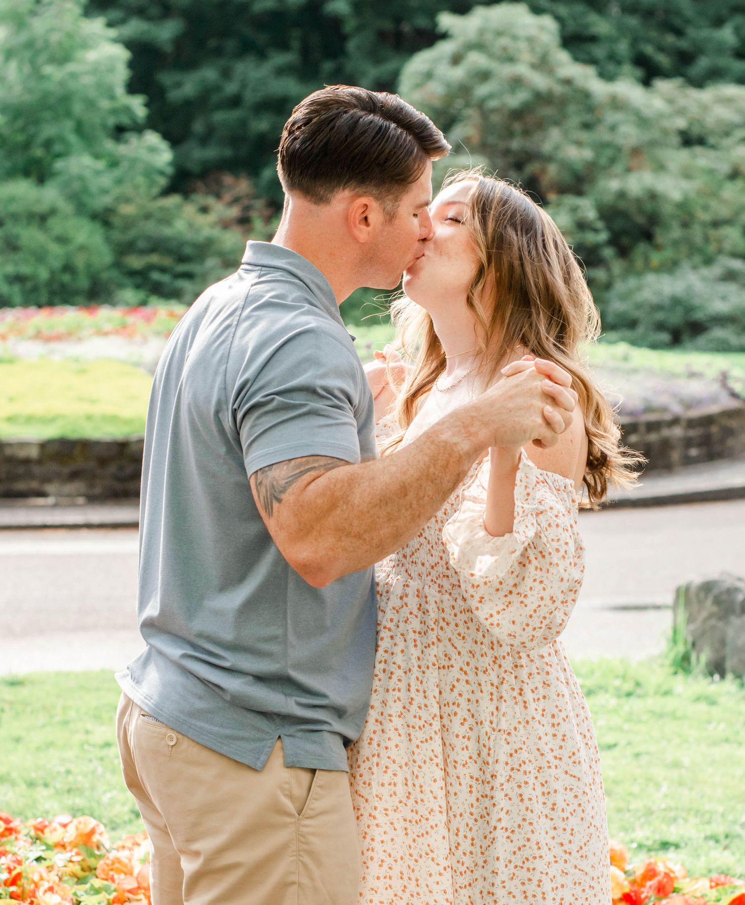 Intimate outdoor portrait in a garden with blooming orange flowers and natural greenery.