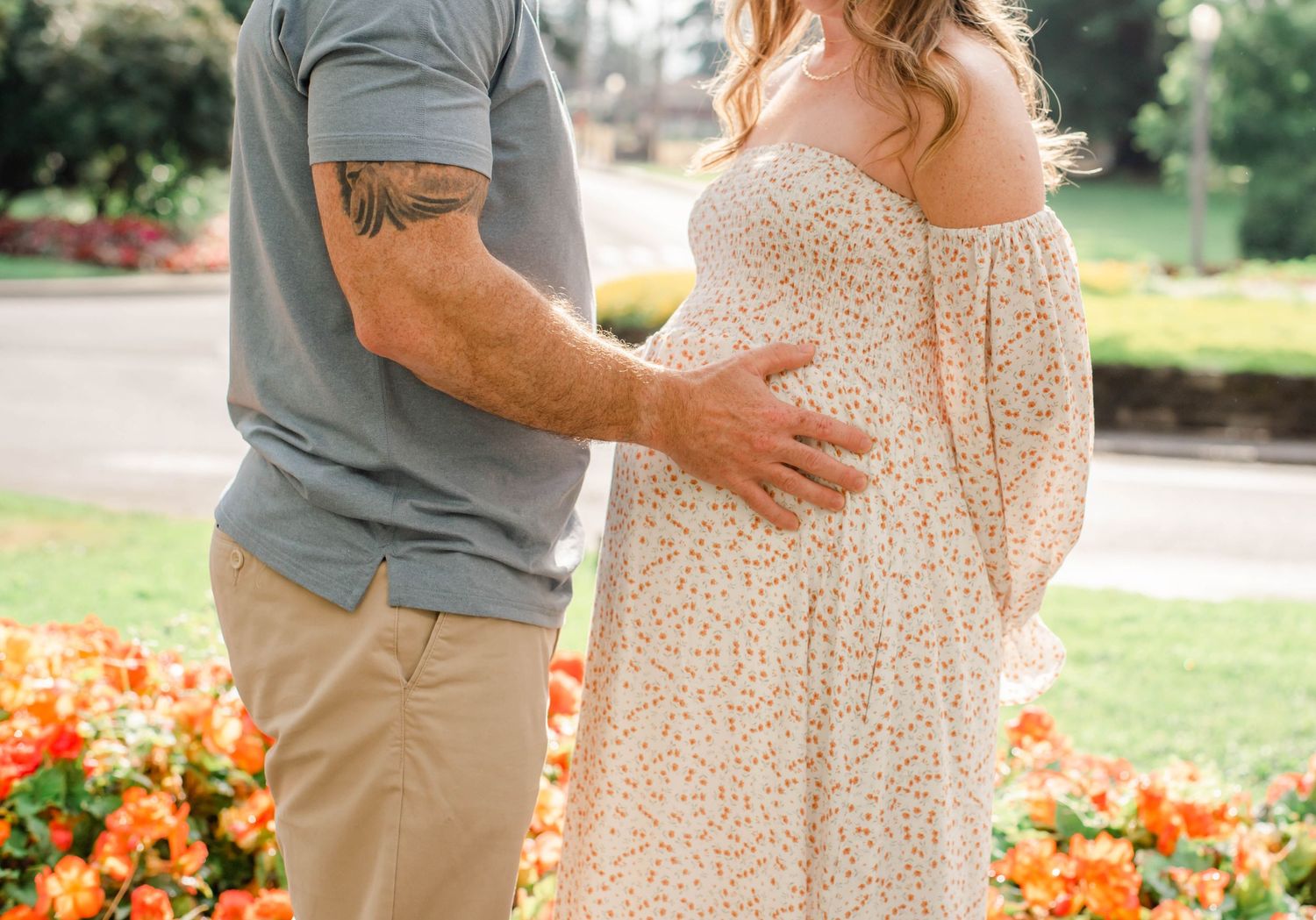 Close-up shot of a floral dress and casual attire against a backdrop of orange flowers in a garden.