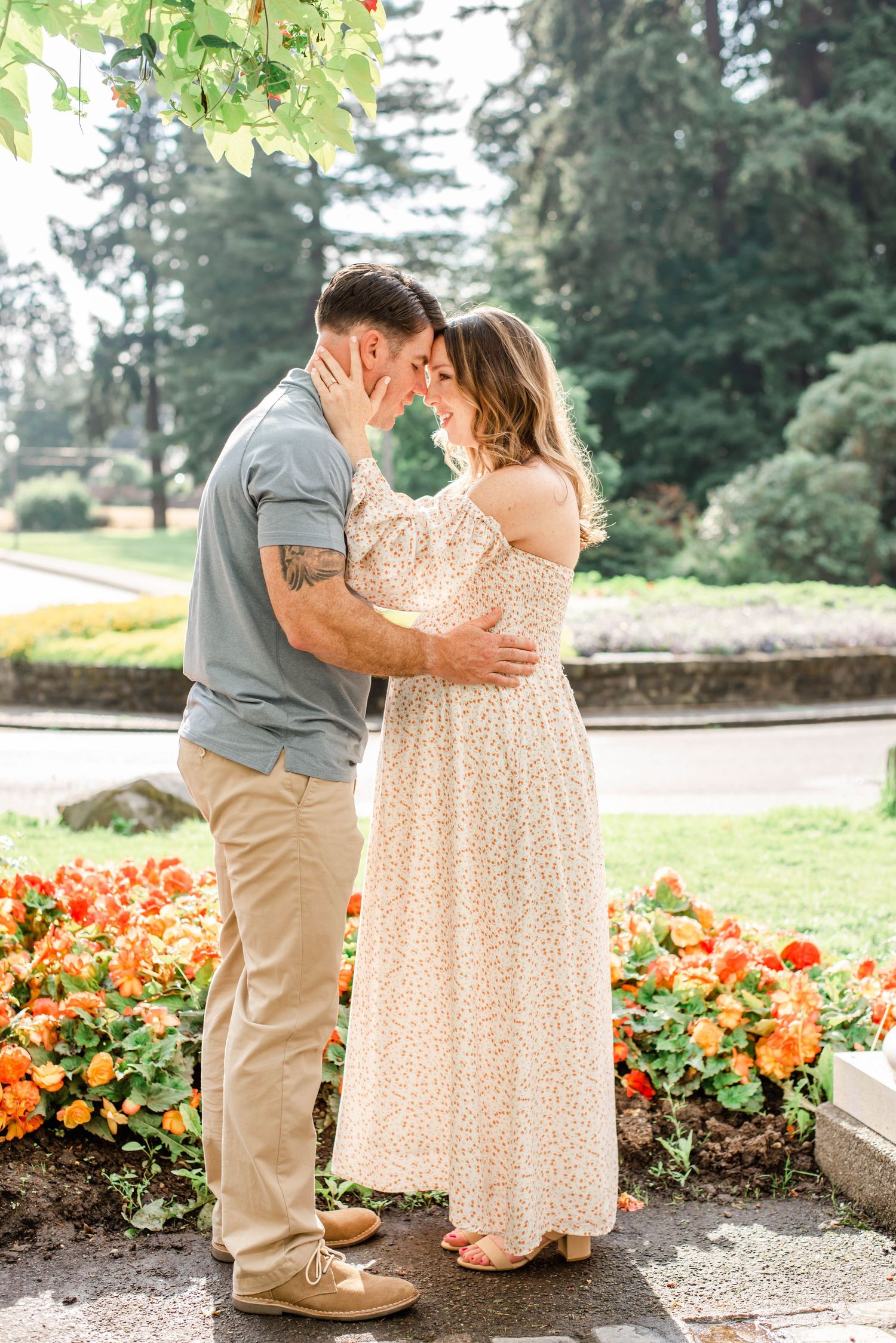 Intimate couple's portrait in garden setting with vibrant orange flowers and evergreens.