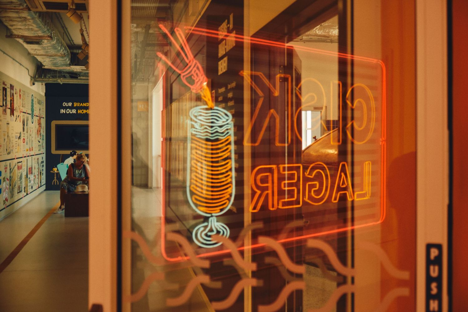 Neon beer sign glowing through a window at night.