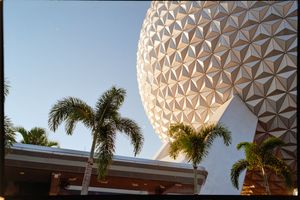Spaceship Earth, EPCOT's iconic geodesic sphere, rises above palm trees during golden hour at Disney World.