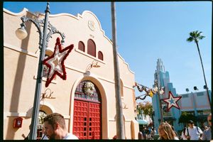 Red doors and decorative stars adorn a Spanish Colonial style building entrance at a theme park with palm trees.