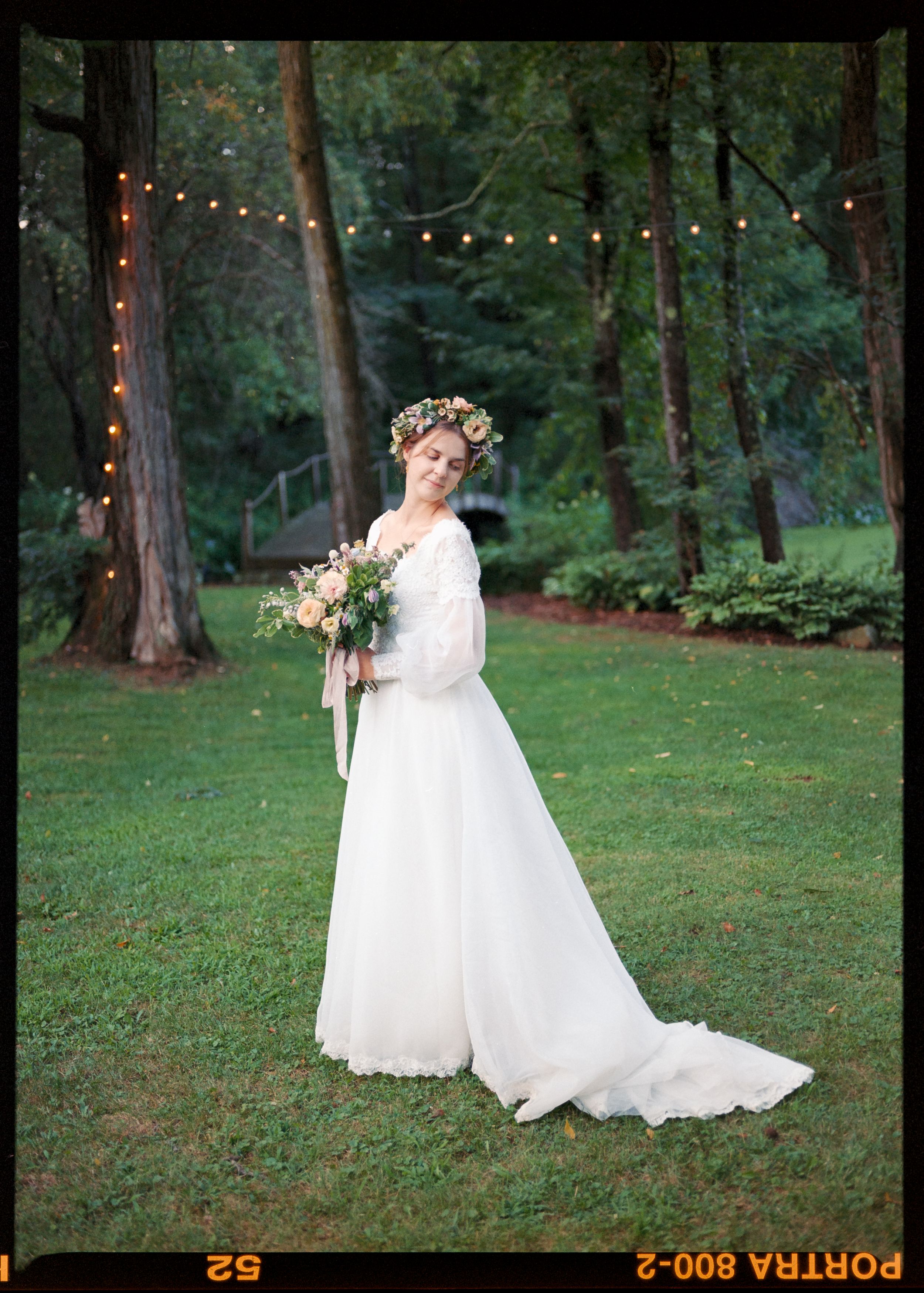 A woodland wedding portrait with string lights and trees creating a magical backdrop.
