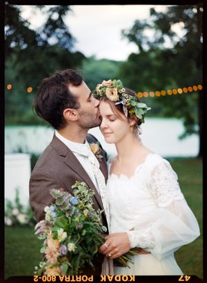 A tender wedding moment captured outdoors with a floral crown and romantic lighting.