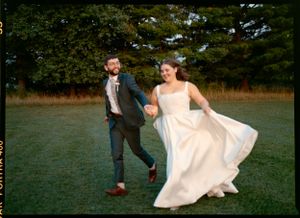 Couple dancing playfully on grass during their wedding photoshoot.