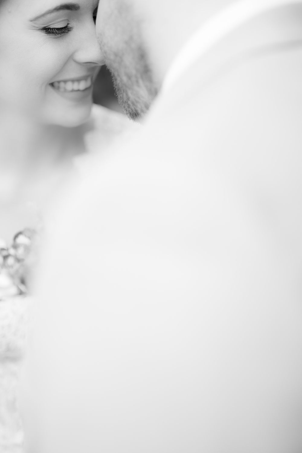 Intimate black and white close-up portrait capturing tender moment between newlyweds.